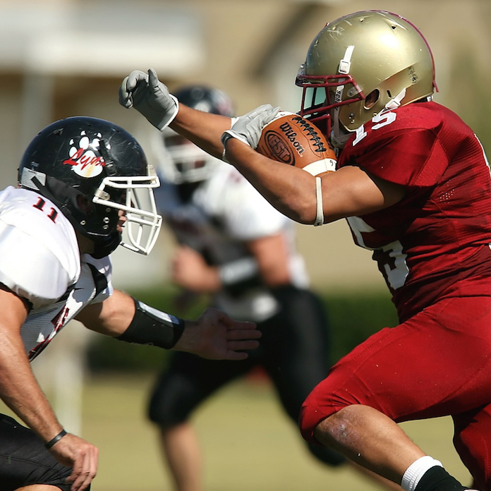 Two grid iron players charging towards one another